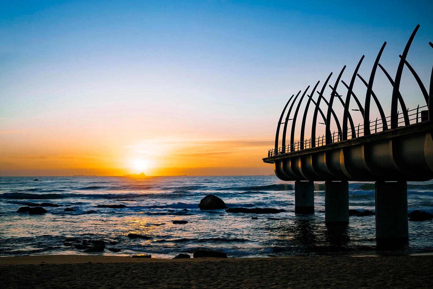 Durban Umhlanga pier in south africa in the golden morning sunrise with ships on the horizon